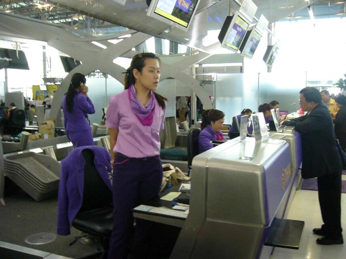 A friendly customer service representative assisting a traveler at an airport counter, representing the contrasting approaches to customer service between Breeze Airways and Allegiant Air